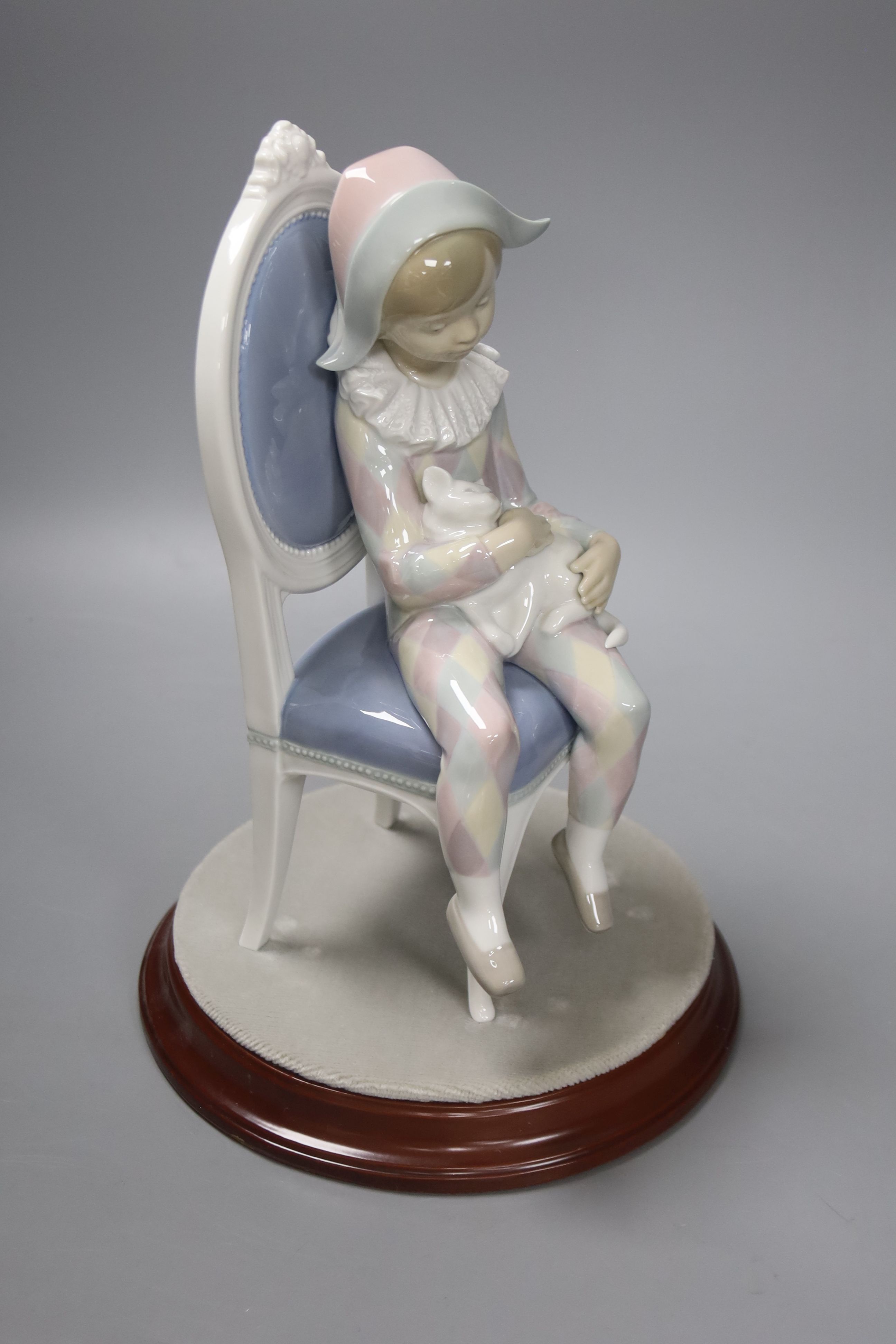 A Lladro figure of Harlequin Boy with cat sitting on a chair, no. 1229, 30cm high